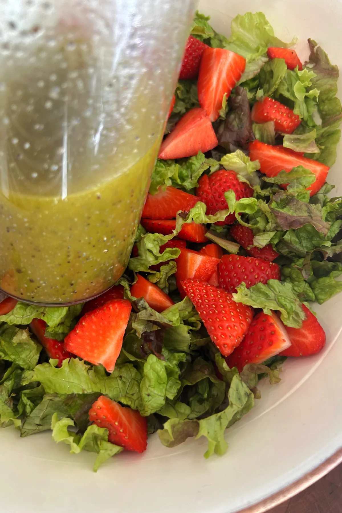 strawberry salad with jar of dressing on top