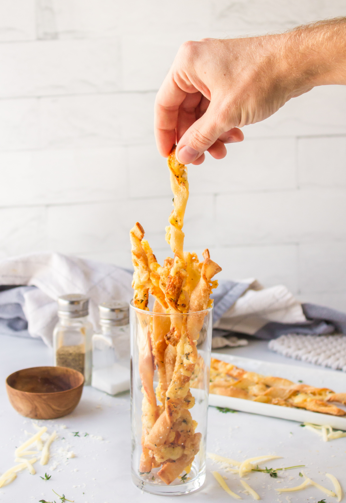 hand picking cheese straw from glass