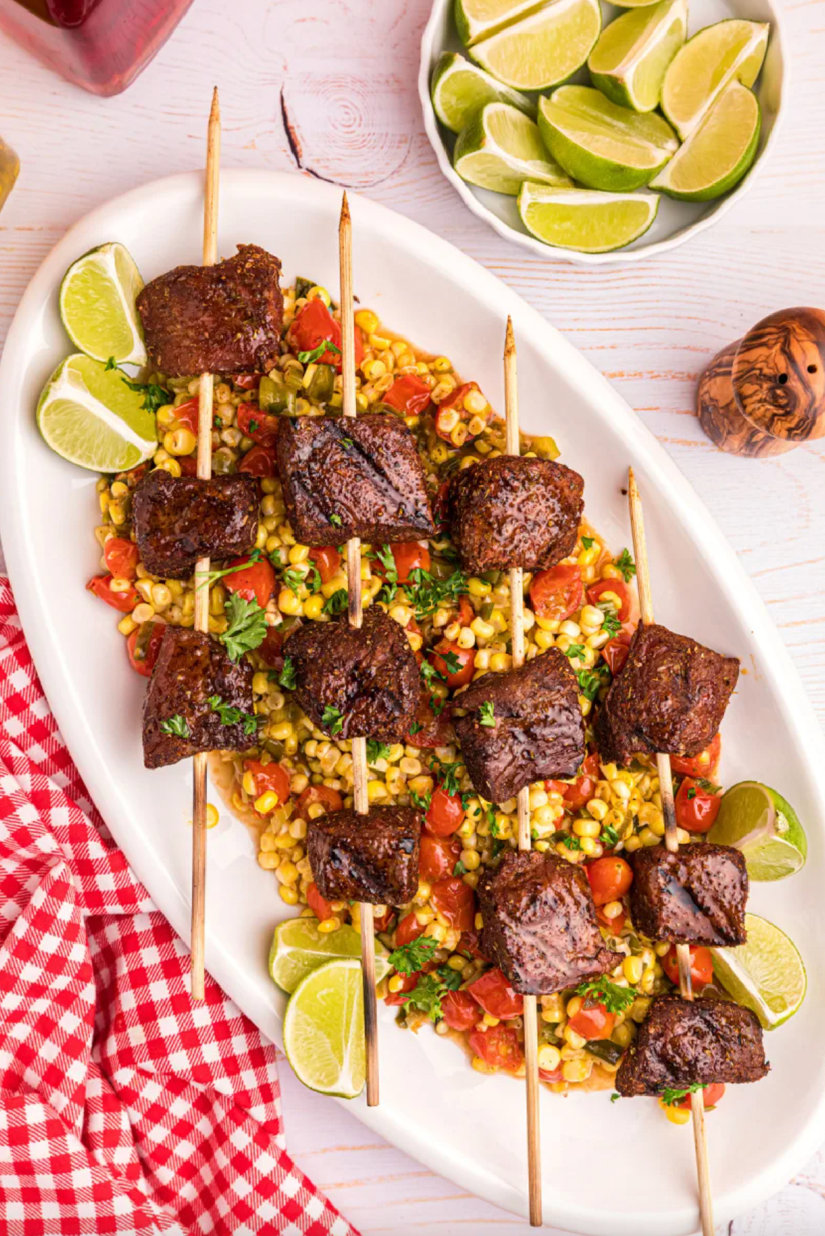 grilled beef kebabs with corn tomato salad on platter