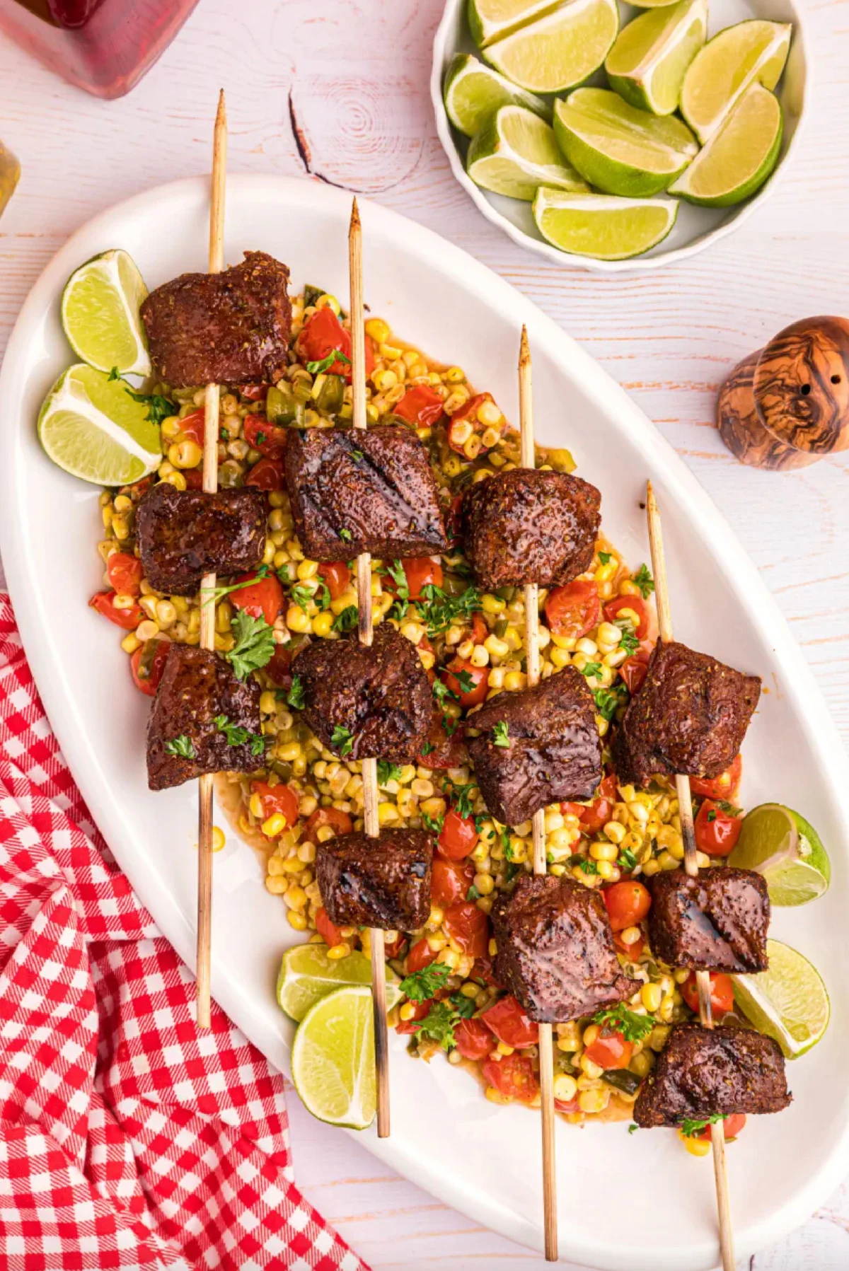 grilled beef kebabs with corn tomato salad on platter