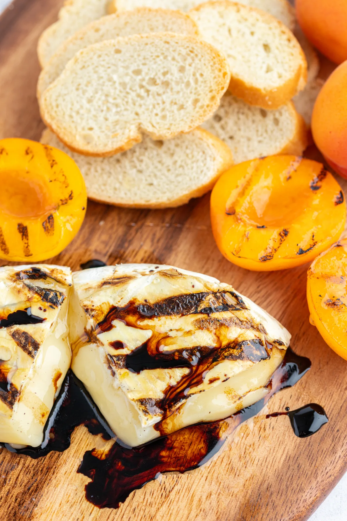 grilled brie cut open on board with balsamic glaze and apricots