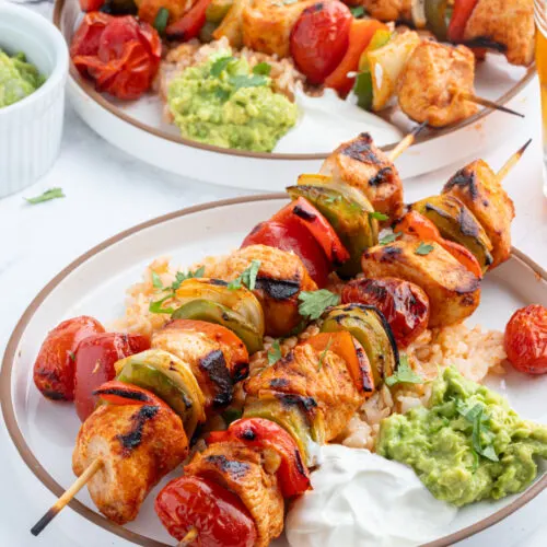 grilled chicken taco kebabs on plate with sour cream and guacamole