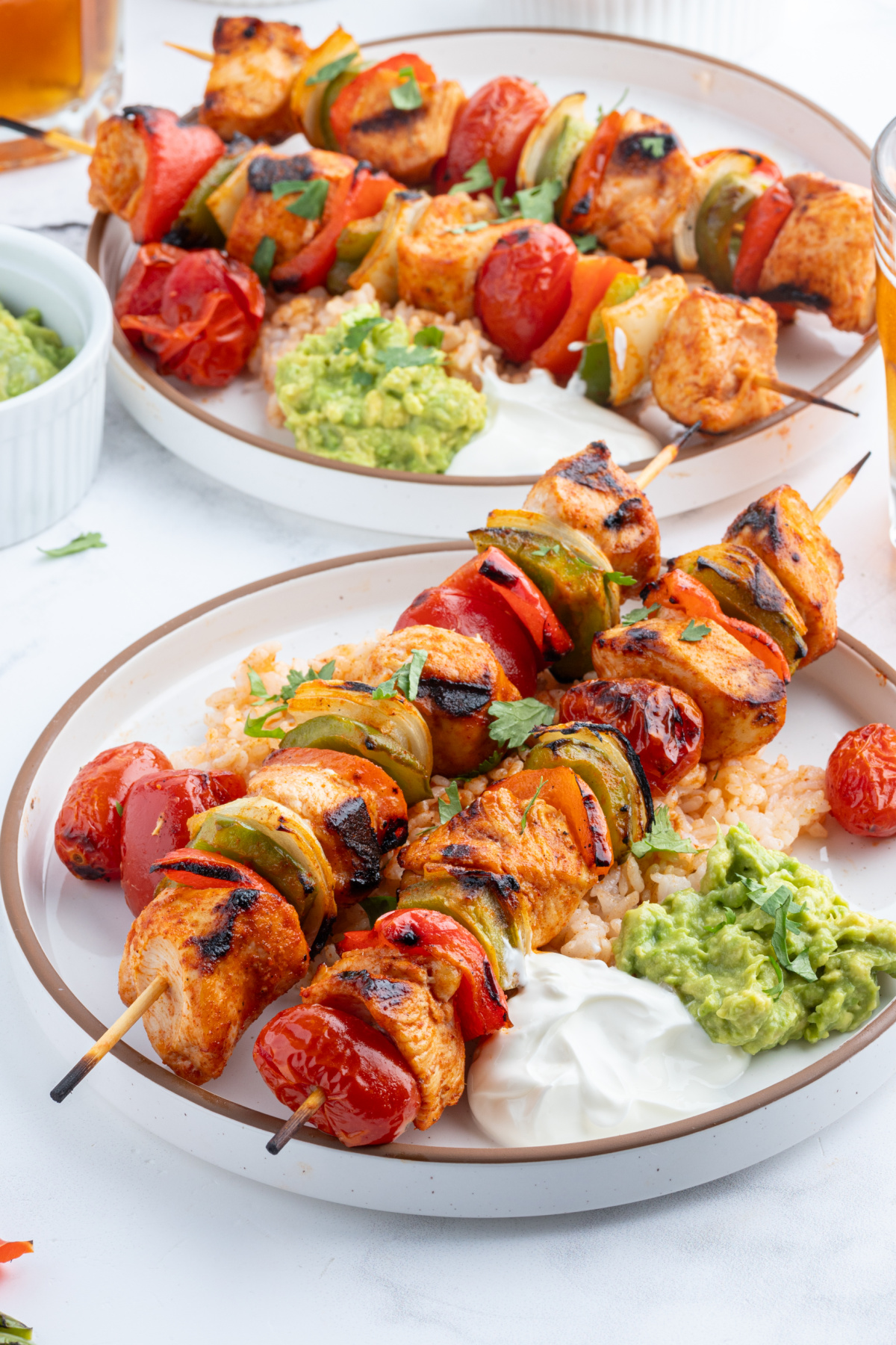 grilled chicken taco kebabs on plate with sour cream and guacamole