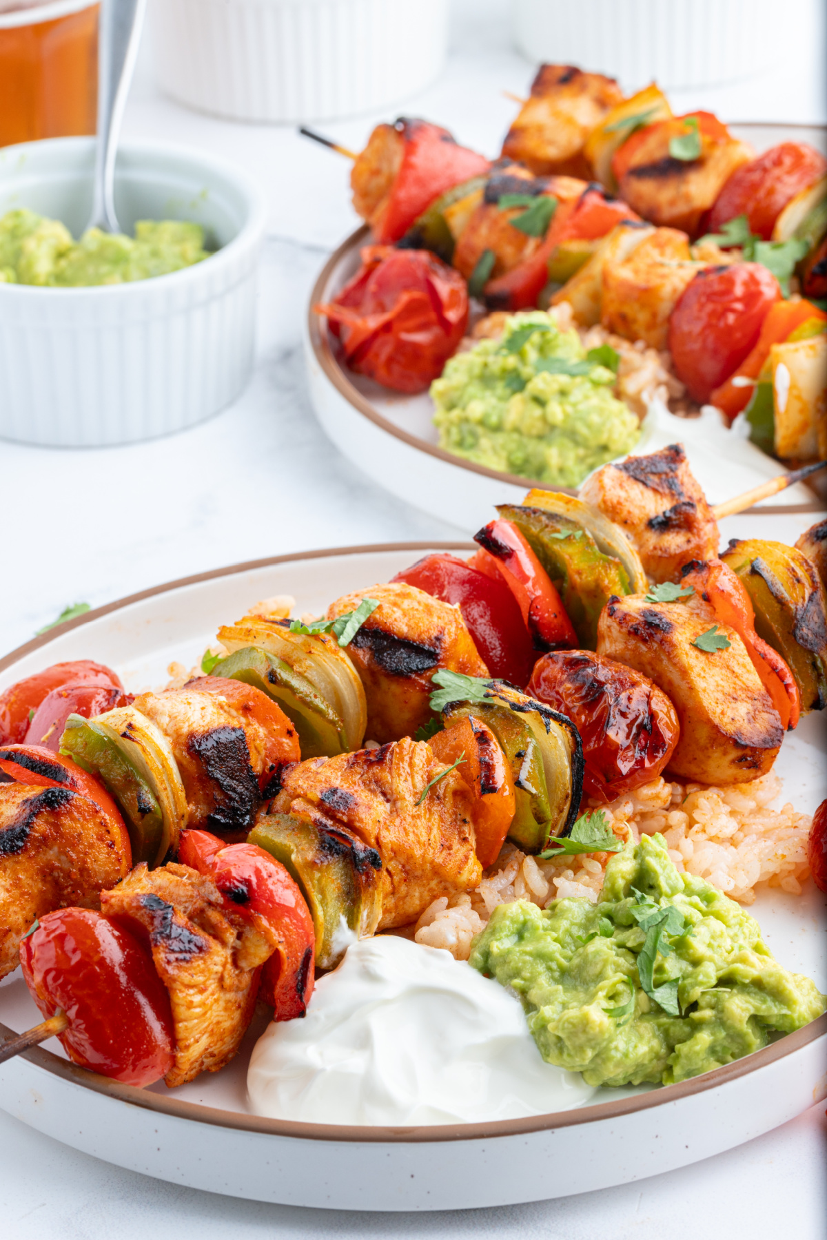 grilled chicken taco kebabs on a plate with guacamole and sour cream