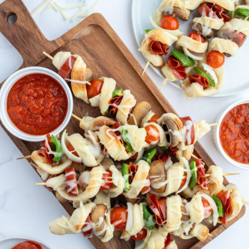 pizza kabobs on cutting board with pizza sauce