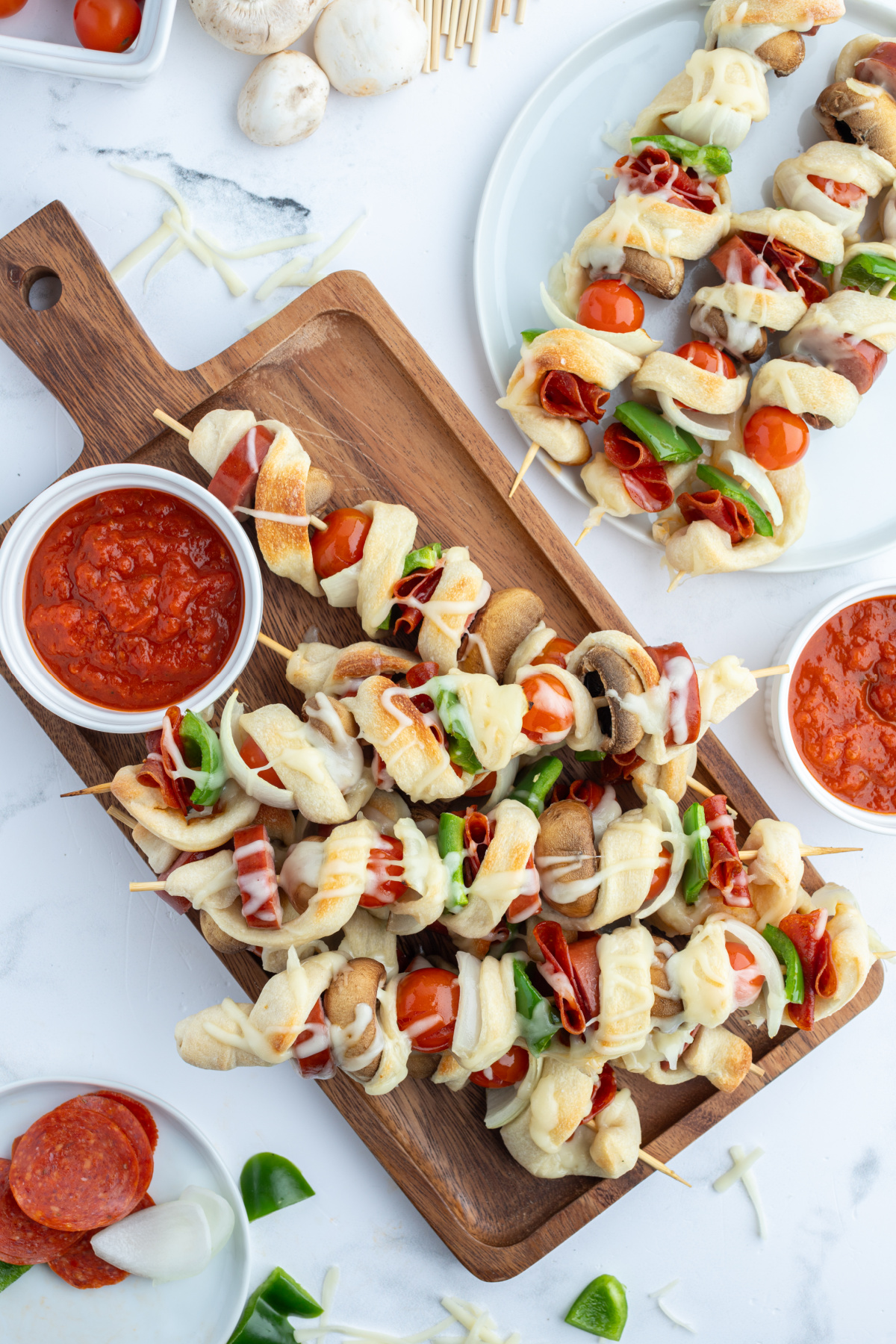 pizza kabobs on cutting board with pizza sauce