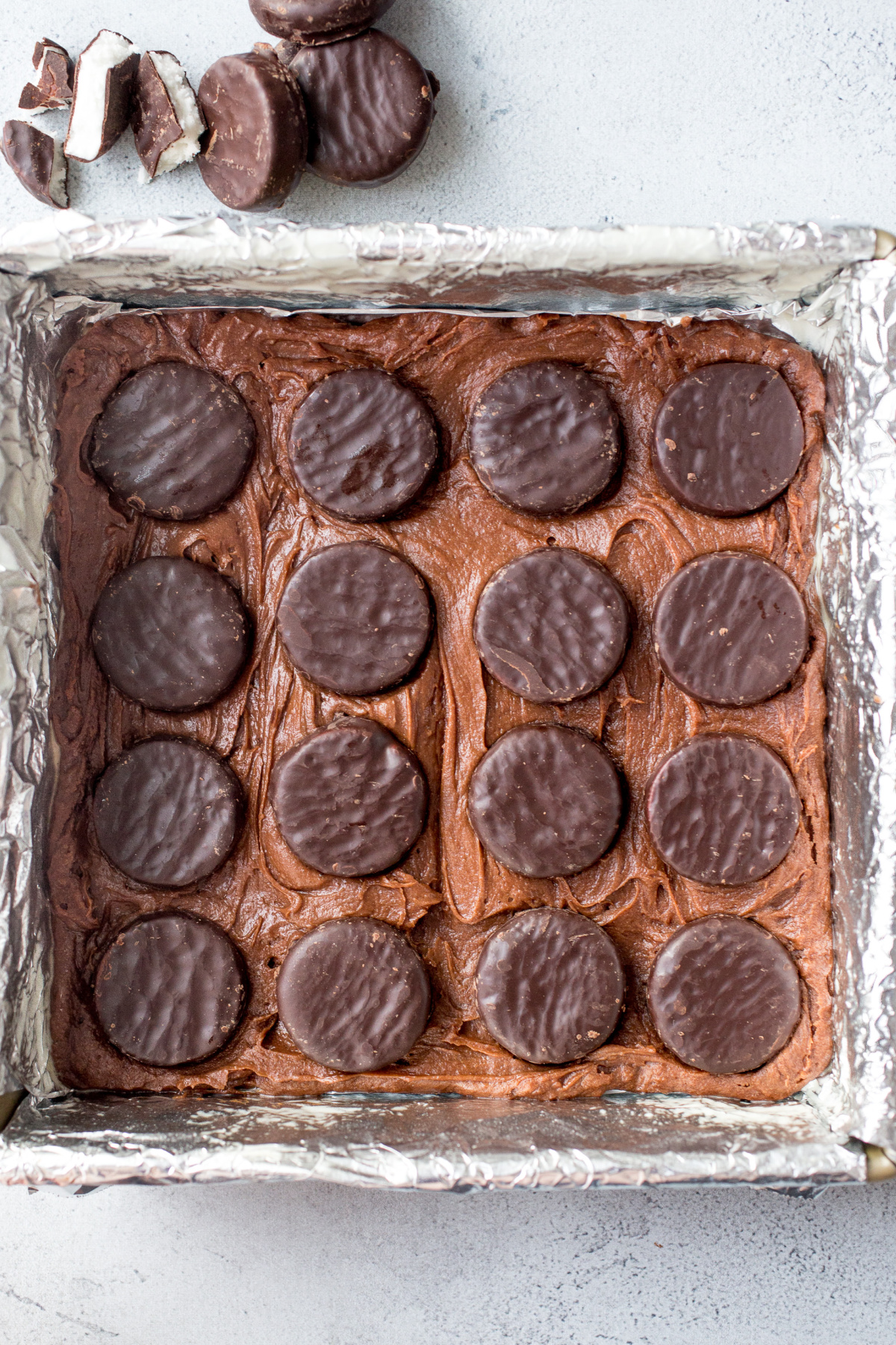 peppermint patties on top of brownie batter in square pan