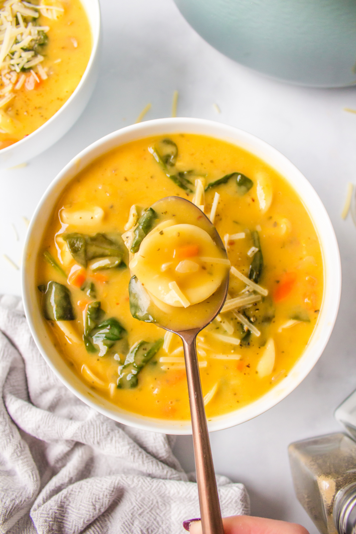 spoon of cheese tortellini soup over bowl