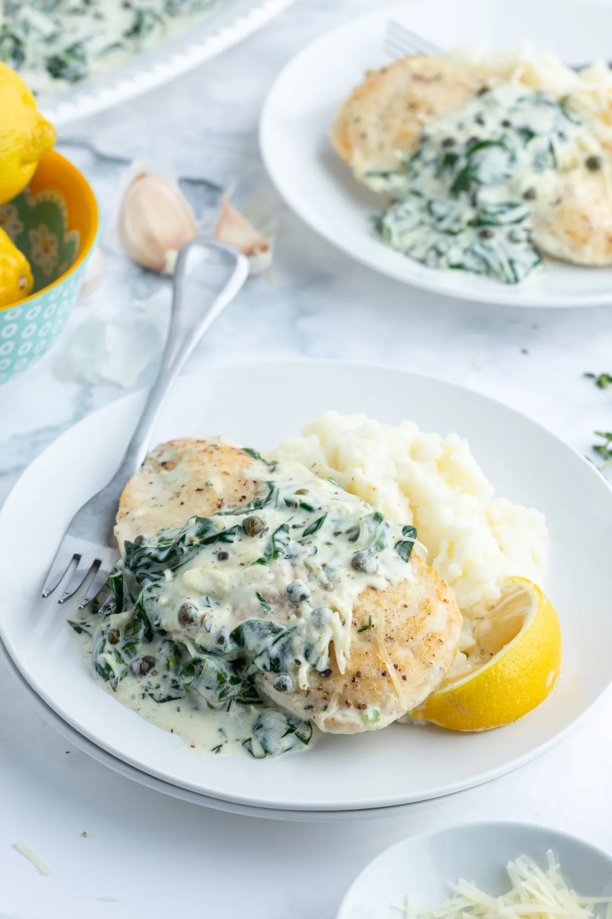 Mediterranean chicken on plate with fork and lemon wedge